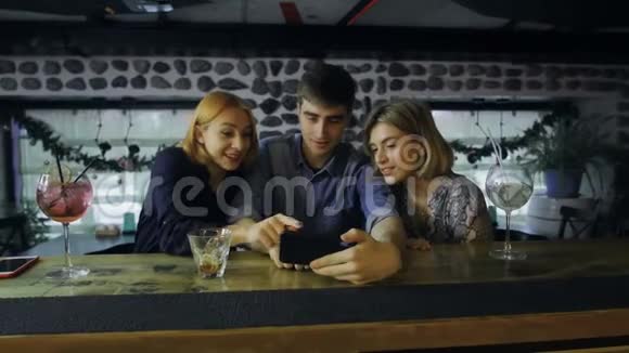 在酒吧吧台使用智能手机的朋友视频的预览图