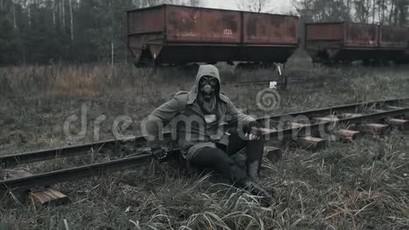 一个戴着防毒面具的人坐在火车上坐在破旧的火车站里视频的预览图