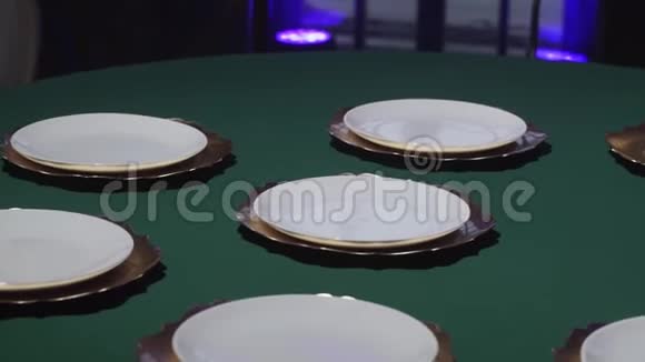 女人的手把白色的盘子和绿色的桌布放在桌子上视频的预览图