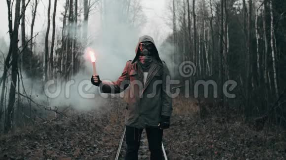 戴着防毒面具的人站在死林中的铁路上手里拿着信号火视频的预览图