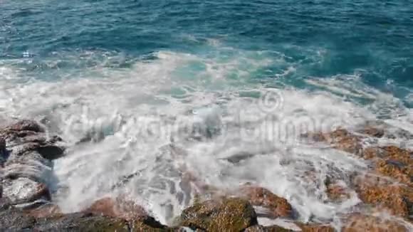 蓝色的海浪拍打着海岸的黄色石头大量白色泡沫和喷雾形式近点视频的预览图