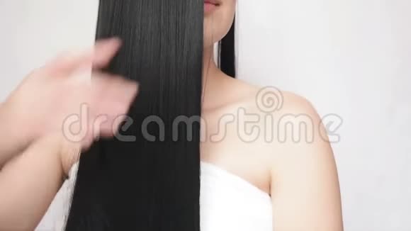 年轻女孩抚摸着长长的头发表现出她们的光滑和丝滑漂亮的女士关心头发视频的预览图
