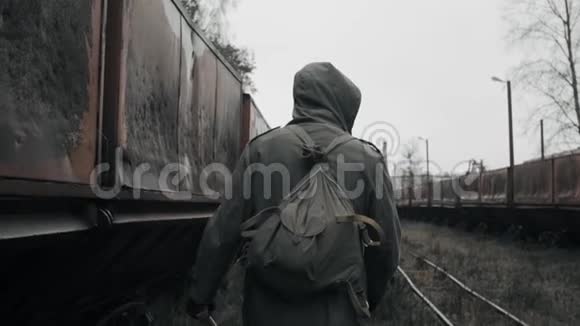 戴防毒面具的人走在被摧毁的火车站废弃的生锈车厢附近视频的预览图