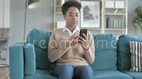 非洲女孩坐在沙发上用电话视频的预览图