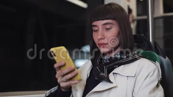 吸引人的年轻女性在公共交通上的智能手机上观看视频晚上特写镜头城市灯光视频的预览图