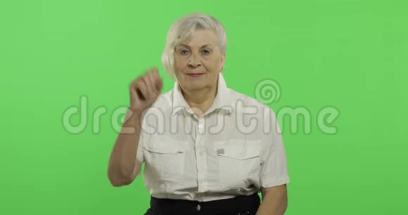 一位老年妇女向镜头挥手微笑老奶奶铬键视频的预览图