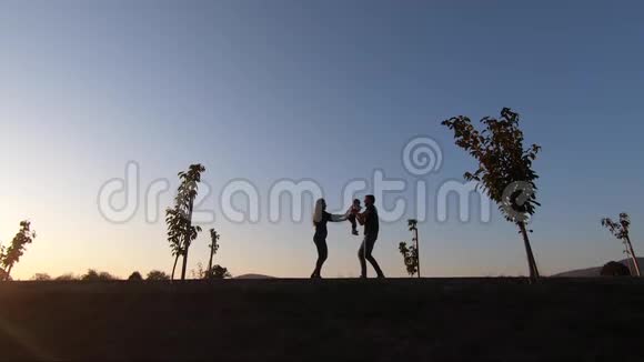 爸爸妈妈和女儿在公园里散步的剪影幸福的家庭在一起视频的预览图