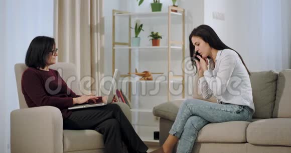 沮丧的女人在心理医生那里接受了治疗她们坐在沙发上耐心地打着电话视频的预览图