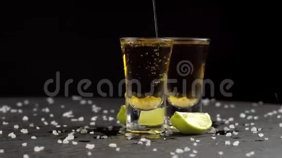 龙舌兰酒在黑色背景下倒入两杯视频的预览图