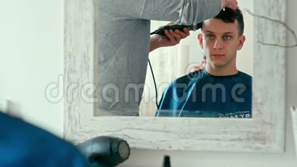 理发师用剪报剪发在理发店沙龙的人镜面反射视频的预览图