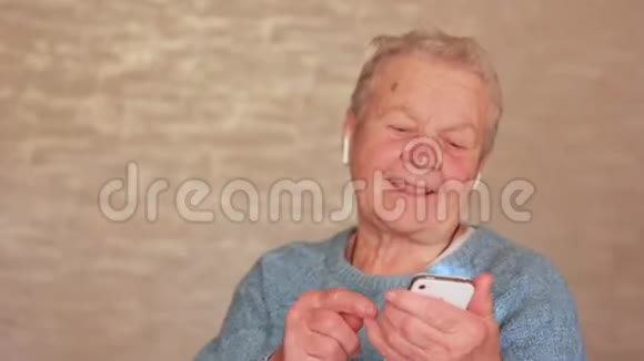 一位戴着耳机和带着手机跳舞的老妇人玩得很开心奶奶戴着耳机视频的预览图