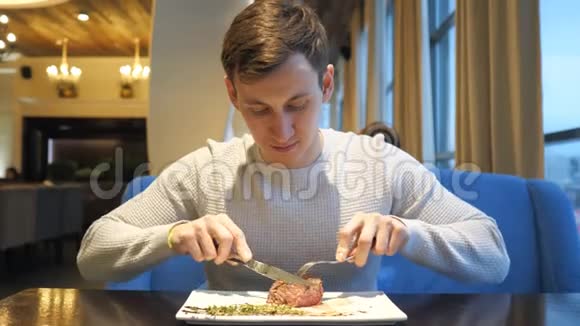 年轻人切肉牛排在餐厅享用晚餐视频的预览图