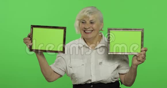 一位老妇人拿着两个带有绿色图像的框架奶奶铬键视频的预览图