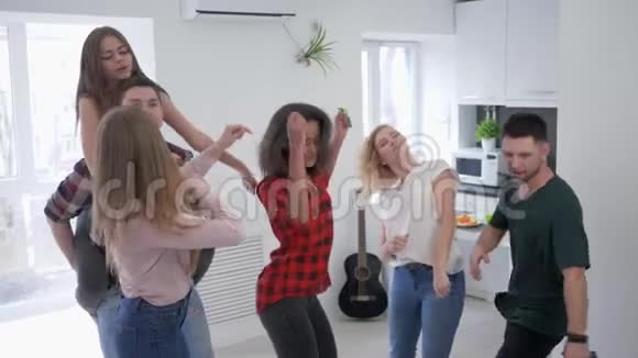 在厨房里玩纸屑的朋友们慢动作多种族的年轻人在家庭聚会上跳舞玩得很开心视频的预览图