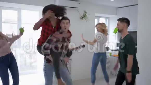 快乐的年轻朋友在家庭聚会上玩跳舞而女孩在公寓里弹吉他视频的预览图