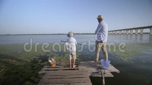 例句3暑假期间小男孩和他快乐的父亲在河边的码头钓鱼视频的预览图