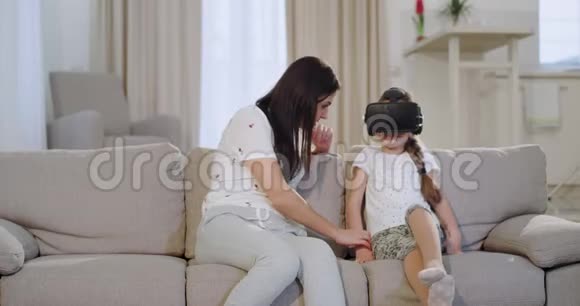 在沙发上的现代客厅里一位成熟的母亲和她的女儿一起度过了一段虚拟现实的时光视频的预览图