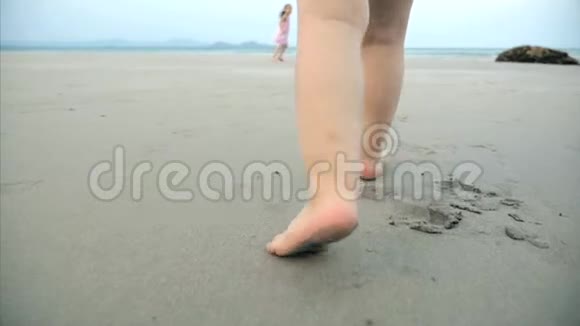 孩子们的剪影在热带海洋背景下沿着热带海滩的湿沙上行走的脚概念视频的预览图