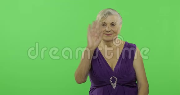 一位老年妇女向镜头挥手微笑老奶奶铬键视频的预览图