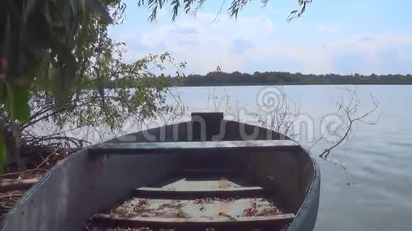 在美丽的夏日阳光明媚的日子里古老的木制划艇漂浮在河岸上的水上视频的预览图
