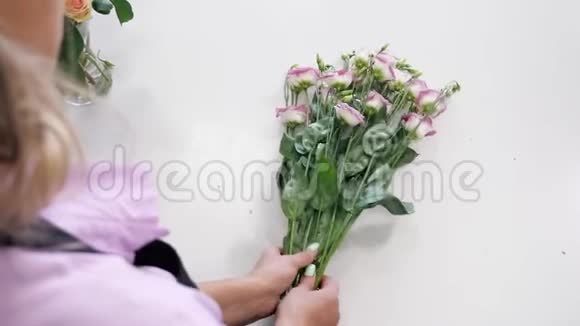 女花艺师工作时桌上放着白色和紫色的花双手特写视频的预览图