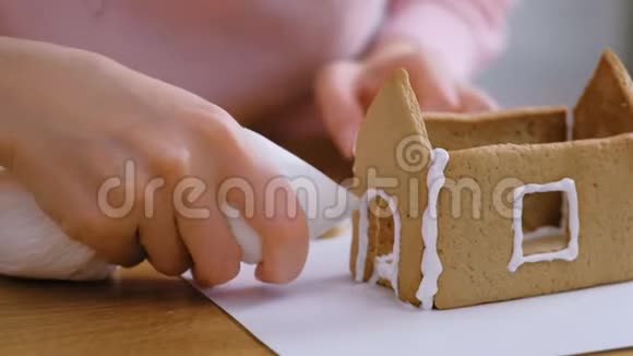 女人的手使姜饼屋的细节与糖甜糖霜烹饪自制姜饼屋视频的预览图