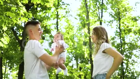 快乐的年轻家庭在外面和女婴玩视频的预览图