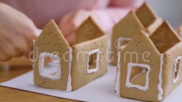 女人手使姜饼屋的细节与糖甜糖霜烹饪自制姜饼屋视频的预览图