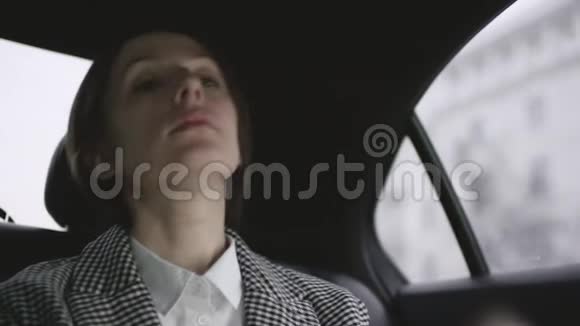 一位穿着白色上衣的棕色头发的女士在车上检查外套并想用一张卡片付款视频的预览图