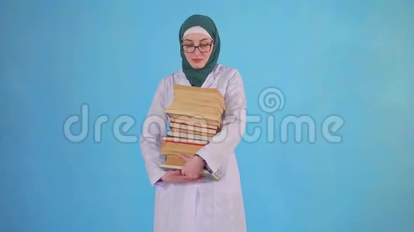 年轻的穆斯林医科学生带蓝色背景的书视频的预览图