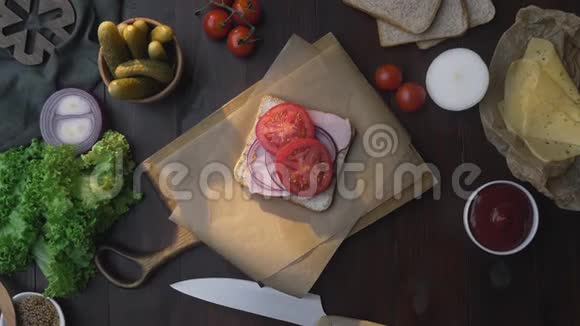 厨师的手补充道三明治的平铺在光线的照射下将火腿和蔬菜切片放在木板上视频的预览图
