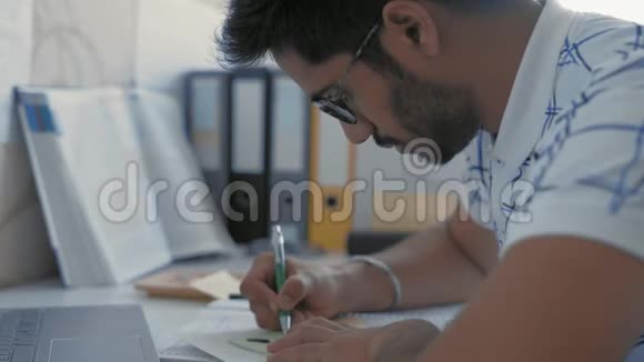 特写戴眼镜的印度学生在贴纸上画草图准备参加医学考试视频的预览图