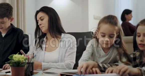 非常可爱的两个妹妹一起在桌上玩游戏而他们的母亲很忙奶奶在后台读一本视频的预览图