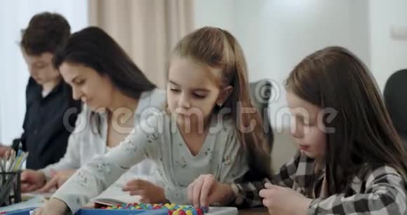 亲密的母亲和她的孩子们在一起他们在客厅里画画和玩桌游非常视频的预览图