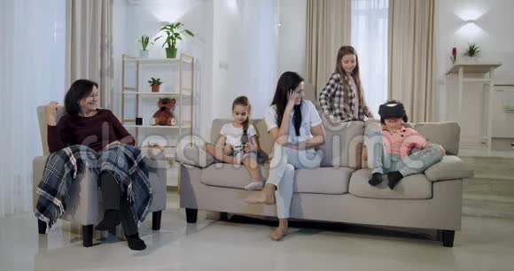 快乐的母亲和她的孩子和一个奶奶一起在客厅里玩他们在一个虚拟的房间里玩视频的预览图