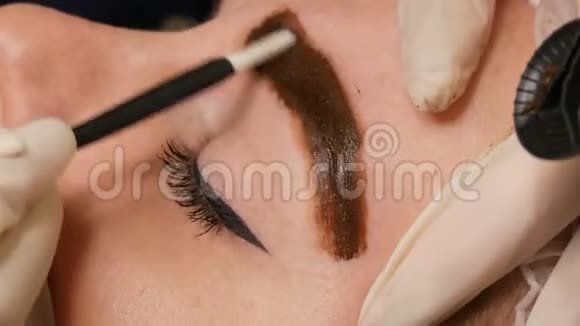 微刃发眉眉毛纹身和永久化妆手套里的师傅把颜料均匀地涂在眉毛上视频的预览图