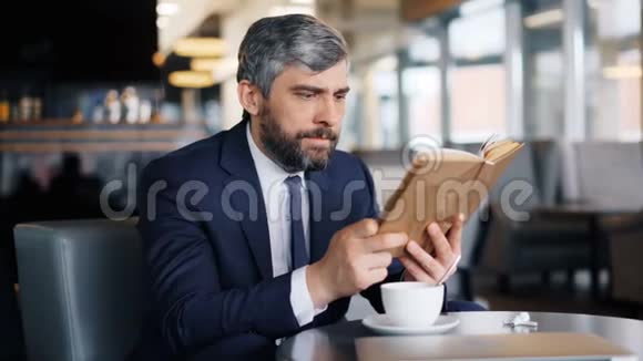 聪明的企业家独自坐在咖啡馆里读书欣赏有趣的故事视频的预览图