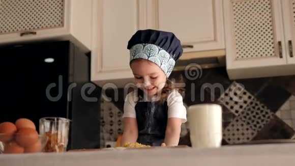 一个三岁的小女孩正在家厨房里玩面团视频的预览图