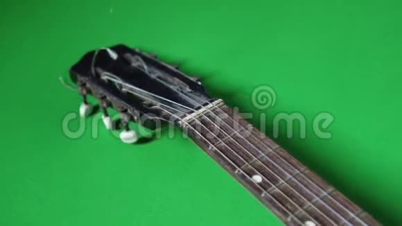 一把绿色地板上有断弦的古吉他视频的预览图