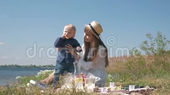 快乐的童年有趣的小男孩吃柠檬和小妈妈一起在河边和天空野餐视频的预览图