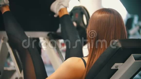 一个运动的女人在健身房锻炼在训练器械上进行腿部按压视频的预览图