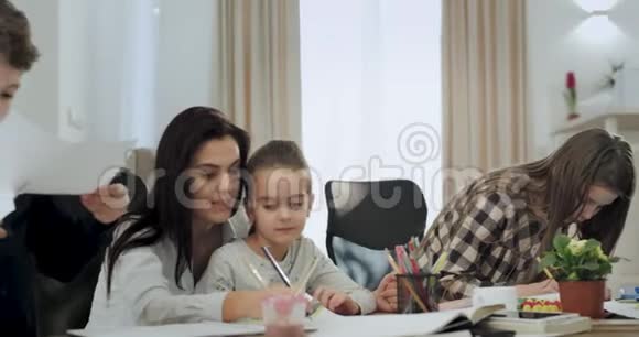 妈妈带着大大的微笑在放学后和孩子们一起在客厅里玩手工游戏视频的预览图