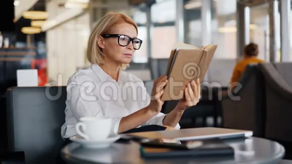 漂亮的成熟商务女士在咖啡厅午休时阅读书籍视频的预览图