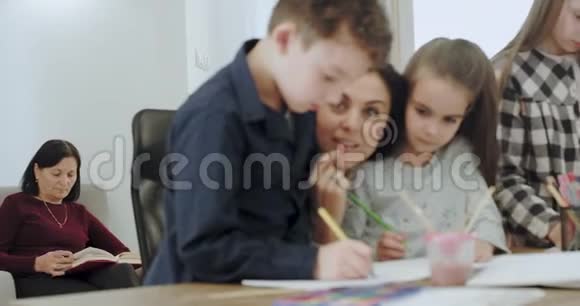 在一个现代化而宽敞的房子里三个孩子和他们的母亲在放学后好好地做家庭作业视频的预览图