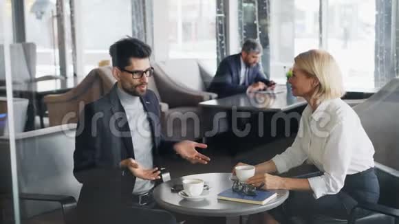 成功的商人成熟的男人和女人在咖啡馆里谈笑风生视频的预览图