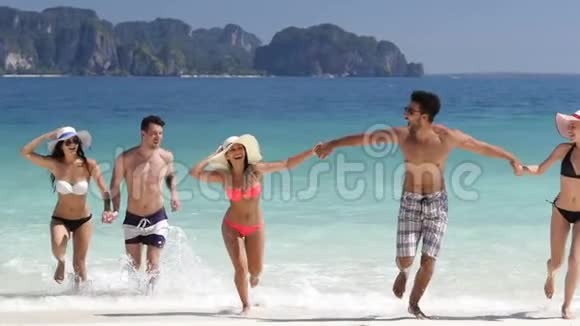 在美丽的海滩上人们手牵着水奔跑男男女女在海上度假视频的预览图