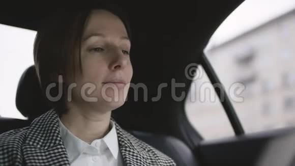穿着白色衬衫穿着外套坐在车里学习工作文件的棕色头发的漂亮女人视频的预览图