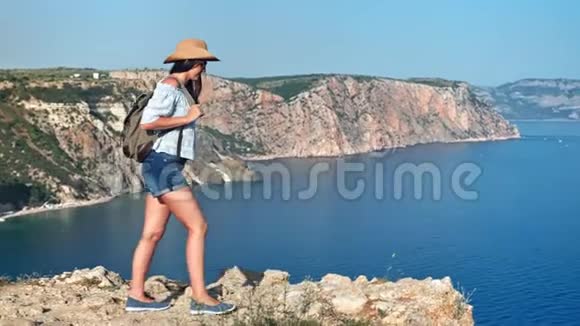 美丽的嬉皮士徒步旅行的女人背着背包走在山顶欣赏令人惊叹的海景视频的预览图