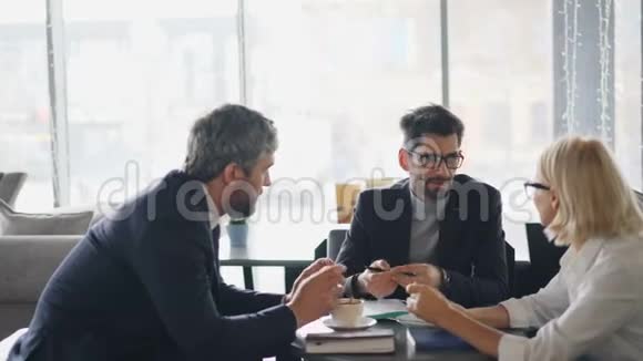 有胡子的男人在咖啡馆里和高级女商人讨论合同细节视频的预览图