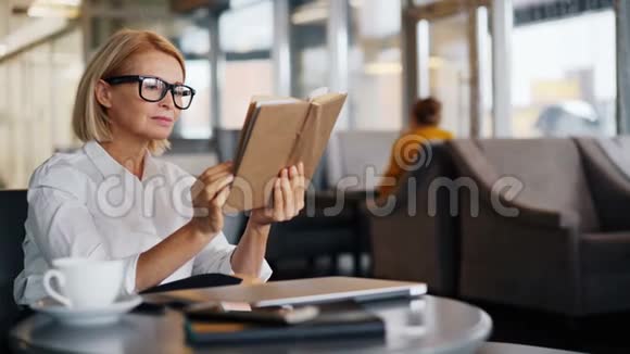 女商人在咖啡休息时在咖啡馆里享受读书的乐趣视频的预览图